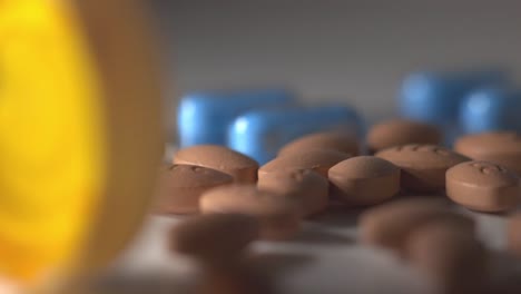 Handful-Of-Brown-Pills-On-Top-Of-A-White-Table-With-Blurry-Background---Closeup-Shot