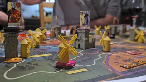 Male-hand-puts-a-toy-windmill-on-fief-board-game---close-up-shot