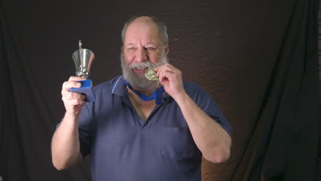 Anciano-Barbudo-Ganando-Una-Medalla-De-Oro-Y-Mostrando-Su-Trofeo