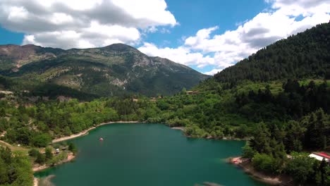 Sliding-right-drone-shot-of-lake-Tsivlou-view-from-above-with-green-mountains-surrounding-peacefully-the-natural-waters