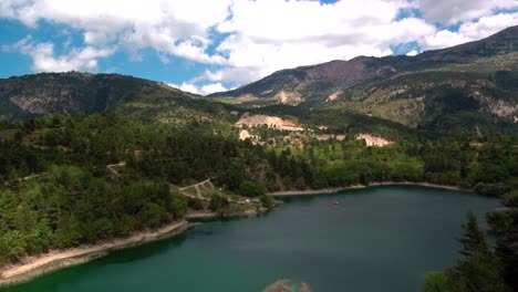 Sliding-right-aerial-parallax-shot-of-lake-Tsivlou-view-from-above-with-green-mountains-surrounding-peacefully-the-natural-waters-on-an-overcast-cloudy-day
