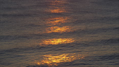 Sunset-casts-shimmering-orange-glow-across-ocean-waves