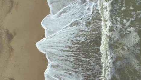Aerial-shot-slowly-rising-of-a-agitated-sea-and-its-powerful-waves-crashing-on-the-beach