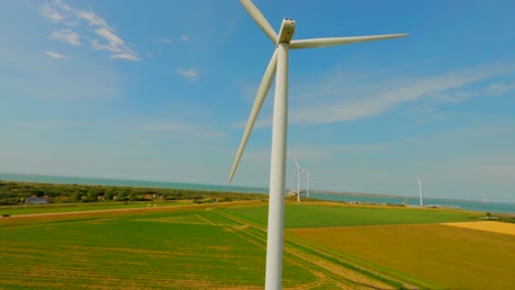 Aerial-drone-crane-shot-of-spinning-wind-turbine-in-green-farm-field