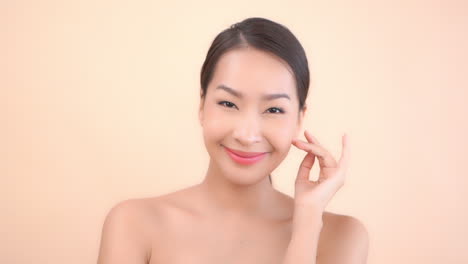 Happy-pretty-asian-woman-after-cosmetic-and-spa-treatment-toucing-her-face-skin-and-looking-at-camera,-close-up-slowmotion