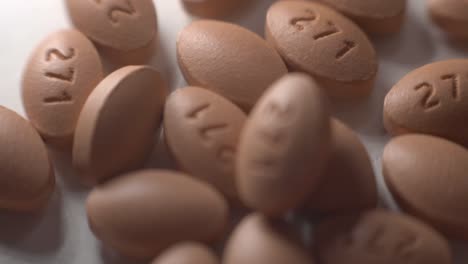 Brown-Oval-Pills-Falling-And-Scattered-On-Top-Of-A-White-Table