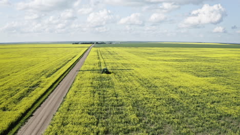Tractor-Rociando-Pesticidas-En-Los-Campos-De-Canola-En-Un-Día-Soleado-En-Saskatchewan,-Canadá