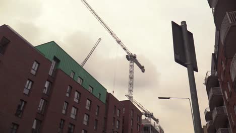 Looking-up-at-a-construction-crane-in-Dublin-city-moving-next-to-an-apartment-complex