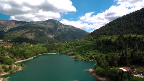 Sliding-right-aerial-shot-of-lake-Tsivlou-view-from-above-with-green-mountains-surrounding-peacefully-the-natural-waters-on-an-overcast-cloudy-day