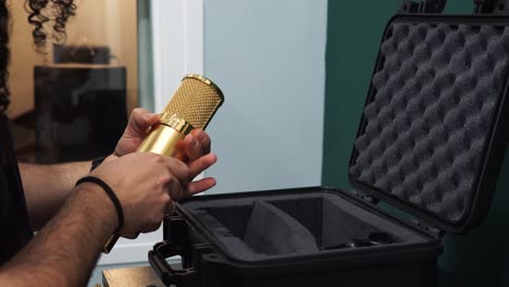 Close-up-shot-of-man-holding-golden-microphone-molded-case-with-foam