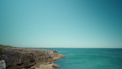 Peaceful-ocean-view-at-shore-with-rock-cliffs-and-blue-sky-at-Cascais-Portugal-4K-jib-shot