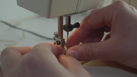 A-static-close-up-view-of-hands-threading-the-needle-on-a-sewing-machine-in-a-mute-environment-with-very-little-amount-color