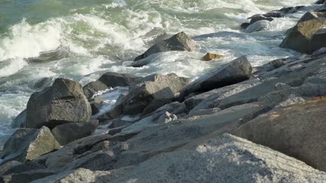 Waves-crashing-against-the-breakwater-rocks-in-sunny-day