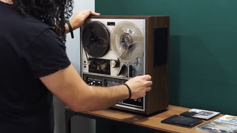 Medium-shot-of-man-fixing-old-vintage-magnetic-audio-reel-to-tape-in-recording-studio