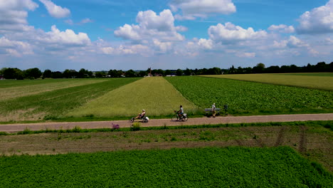 Bicyclists-cycling-between-beautiful-green-fields-in-typical-Dutch-landscape