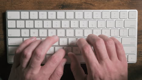Top-down-close-up-of-male-hands-typing-on-bluetooth-keyboard
