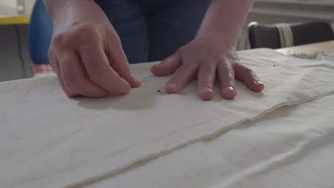 A-seamstress-pins-the-folds-of-fabric-laid-across-a-table