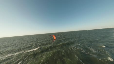 Aerial-drone-flight-above-wind-kite-surfer-riding-waves-in-strong-wind
