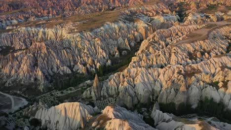 Cappadocia-landscape-with-tuff-stone-formations-after-sunrise,-tilt-down-aerial
