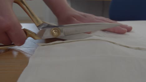 Following-the-view-of-immaculate-metallic-scissors-cutting-a-path-through-some-cloth