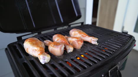 Raw-seasoned-chicken-drummies-being-placed-on-barbecue-grill