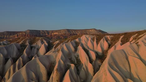 Cappadocia-landscape-with-tuff-stone-formations-during-sunset,-forward-aerial-reveal