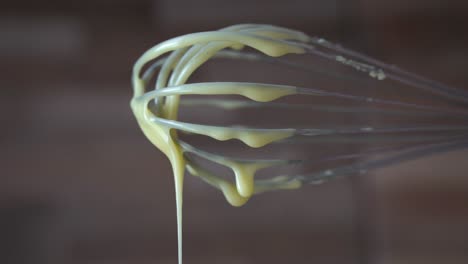 Thick-creamy-yellow-sauce-dripping-of-ballon-whisk