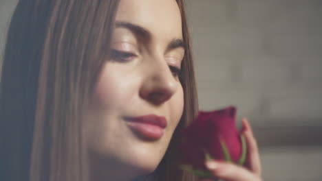 A-young-brunette-woman-sniffs-the-red-roses-flowers-aroma-and-smiling,-Close-up-view