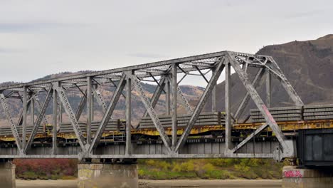 Ein-Güterzug,-Der-An-Einem-Bewölkten-Herbsttag-Den-South-Thompson-River-über-Die-CNR-Brücke-In-Der-Nähe-Des-Riverside-Park-östlich-Der-Innenstadt-Von-Kamloops-überquert