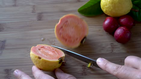 Hände-Schneiden-Reife-Gelbe-Apfel-Guava-Frucht-Mit-Einem-Messer,-Das-Innen-Rosa-Enthüllt