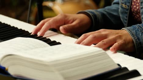 Close-up-of-a-woman-playing-the-keyboard,-hymnal-in-the-foreground
