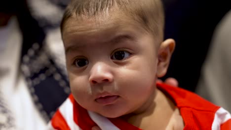 Close-Up-Of-Cute-UK-Asian-Indian-Baby-Boy-Starring-Into-Space-Whilst-Being-Patted-On-His-Back