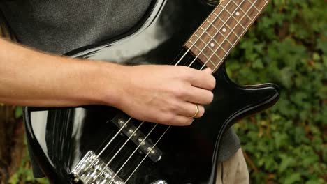 man-stops-playing-electric-bass,-outside
