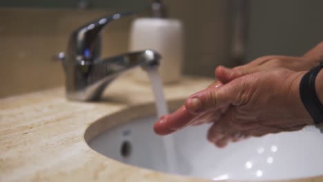 Zeitlupe,-Nahaufnahme-Eines-Alten-Mannes,-Der-Sich-Die-Hände-Mit-Wasser-Und-Seife-Wäscht