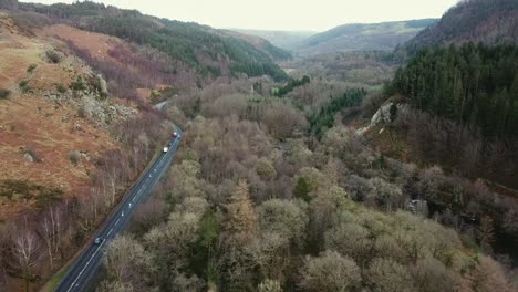 Aerial-view-of-Welsh-valley-and-cars-on-a470,-dense-forest-day-time-Wide-shot-Wales