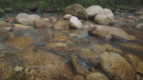 Small-river-full-of-rocks-in-a-beautiful-place-in-slow-motion,-very-detailed,-warm
