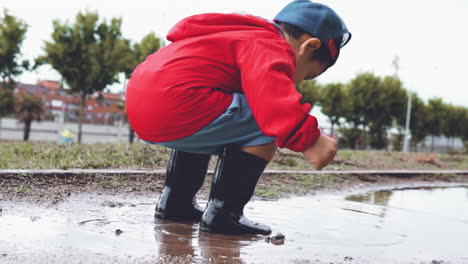 Kid-wearing-rubber-boots-jumping-in-a-puddle-in-slow-motion