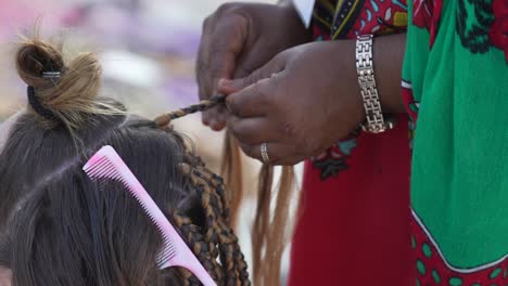 Traditionelle-Afrikanische-Frau,-Die-Einem-Touristenmädchen-In-Ihrem-Haar-Zöpfe-Macht