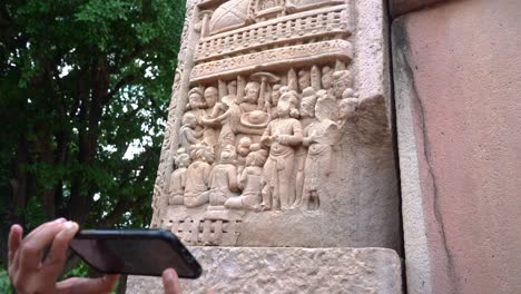 A-Woman-With-Smart-Phone-Capturing-The-Pillar-Carving-At-The-Great-Stupa-In-Sanchi,-Madhya-Pradesh,-India