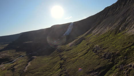 Icelandic-waterfall-by-mountain-side,-sunny-landscape