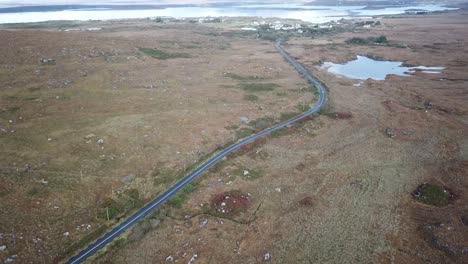 irish-landscape,-aerial-view-in-Connemara,-road-and-brown-meadows,-some-lakes