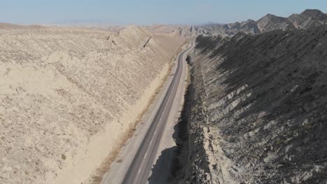 Aerial-Flying-Over-Empty-Makran-Coastal-Highway-Road-Beside-Dramatic-Rock-Formations-In-Hingol-National-Park