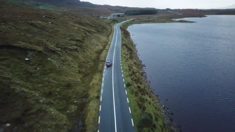aerial-scenic-view-of-a-car-driving-in-connemara,-ireland,-near-the-ocean