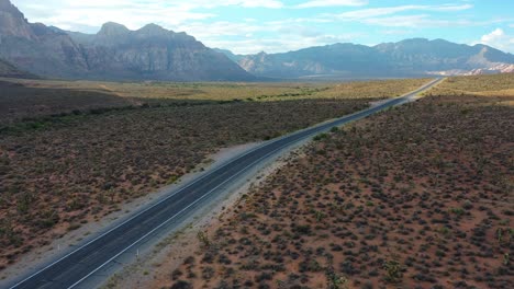 Aerial-drone-shot-of-an-empty-road-highway-with-mountains-in-the-background
