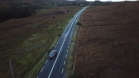 aerial-view-of-a-car-driving-on-a-countryside-road-in-Connemara,-Ireland