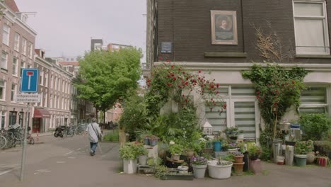 Static-shot-of-a-typical-Amsterdam-street-with-people-walking-next-to-a-beautiful-plant-store-on-a-spring-day