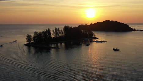 Breathtaking-sunset-landscape,-aerial-flyover-capturing-glowing-sun-setting-behind-paradise-101-and-pulau-burau-island,-reflection-on-calm-sea-ocean,-tropical-paradise-at-Langkawi,-Kedah,-Malaysia
