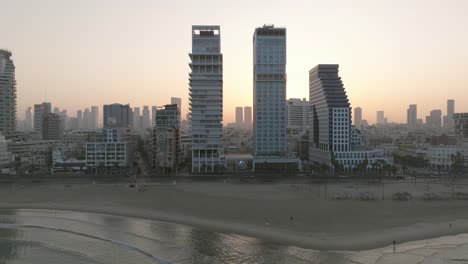 Tel-Aviv-coastline-at-sunrise-with-beautiful-calm-waters-of-The-Mediterranean-Sea,-Waterfront-hotels-and-light-sun-flare