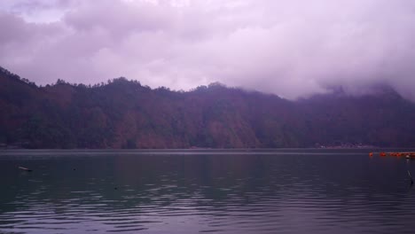 Quick-motorboat-passes-by-Lake,-Mountain-Backgrund-with-Misty-Clouds,-Kintamani-Bali,-Time-Lapse