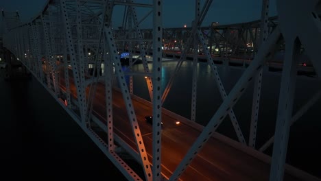 Rising-aerial-of-New-Orleans-skyline-at-night-from-bridge-view-with-lights